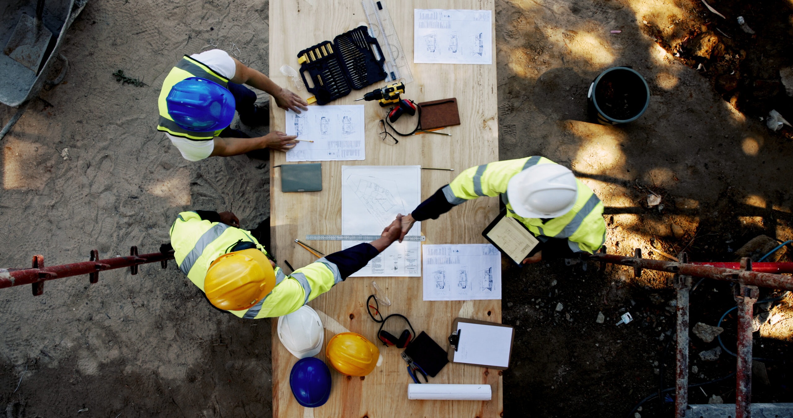 Young black African man construction worker holding clipboard while using mobile phone at building site vertical shot