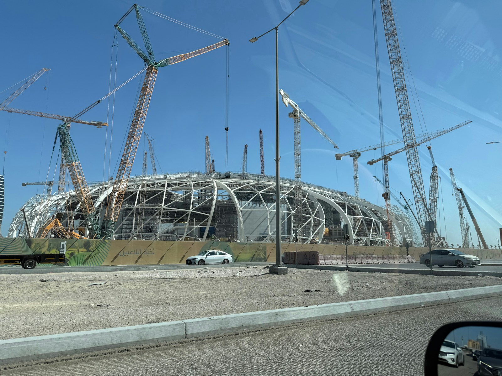 Large stadium construction with many cranes and steel framework.