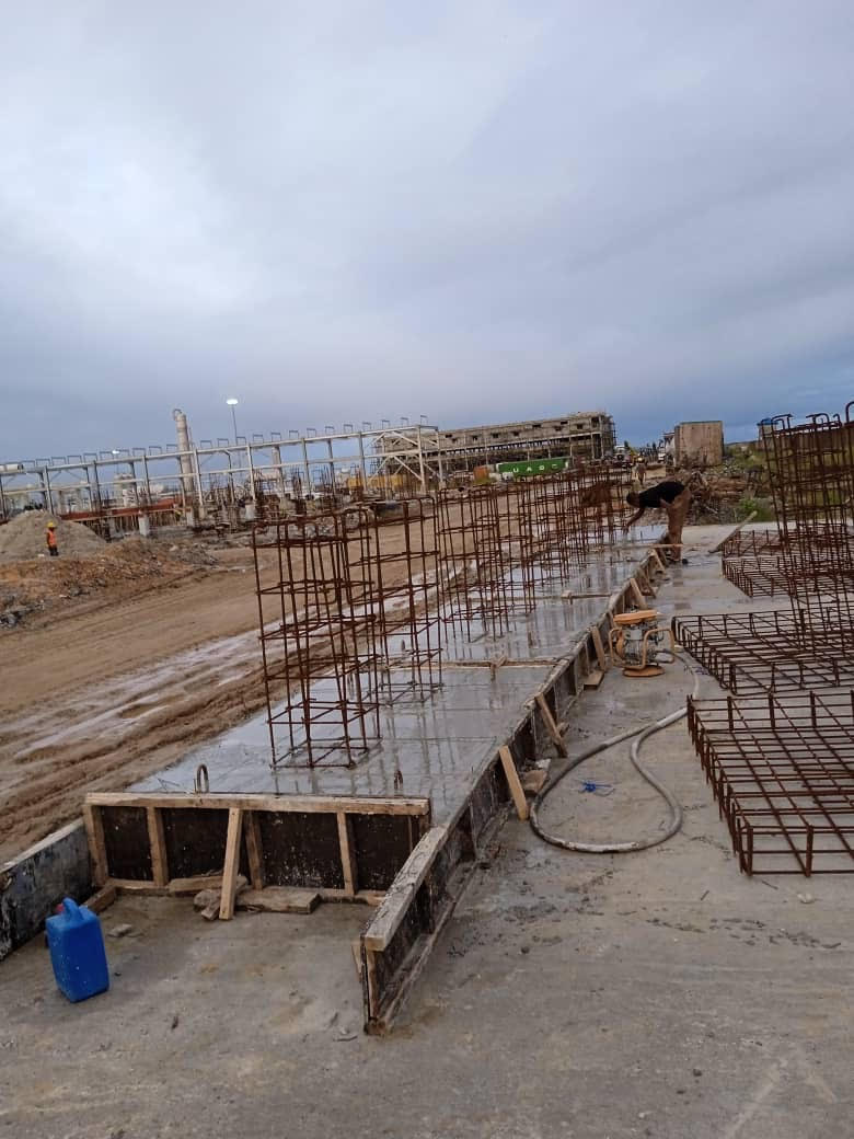 Construction site with reinforced concrete slabs and rebar structures under a cloudy sky, indicating ongoing building development.